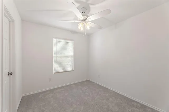an empty room with a window and a fan