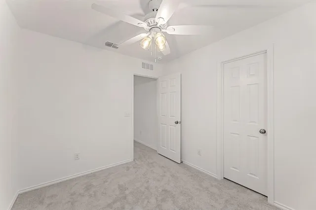 an empty room with a chandelier fan and closet
