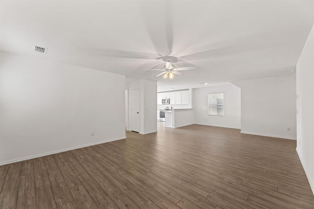 816 Breakwater Drive Princeton, TX 75407 - Photo 6 of 30 a view of a room with wooden floor and a ceiling fan