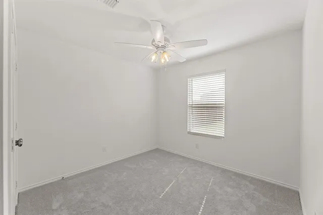 an empty room with a window and ceiling fan