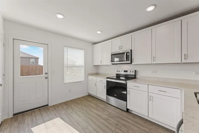 a kitchen with granite countertop white cabinets and stainless steel appliances