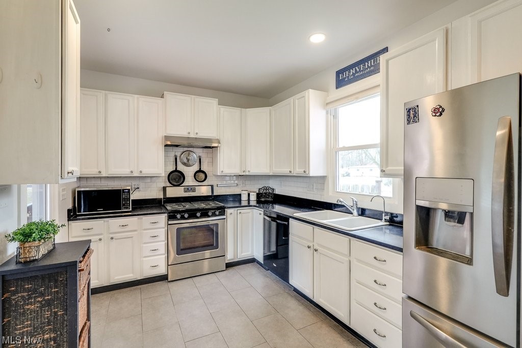 3196 Wadsworth Road Barberton, OH 44203 - Photo 5 of 49 Fully renovated kitchen with ceramic sink, appliances with stainless steel finishes, back splash, light tile floors, and updated white cabinets