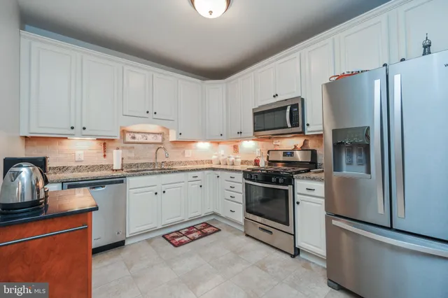 a kitchen with granite countertop stainless steel appliances and white cabinets