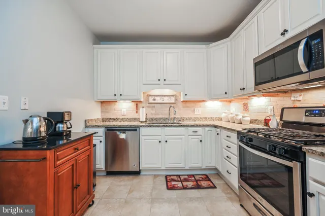 a kitchen with stainless steel appliances granite countertop a stove top oven a sink dishwasher and a microwave oven on the blue kitchen countertops