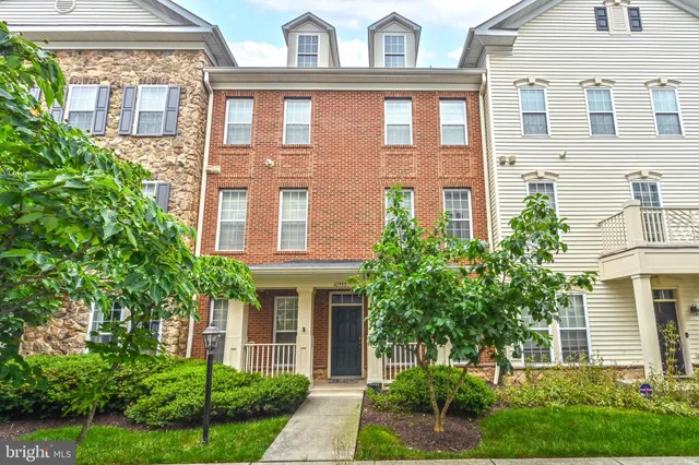 a front view of a residential apartment building with a yard and potted plants