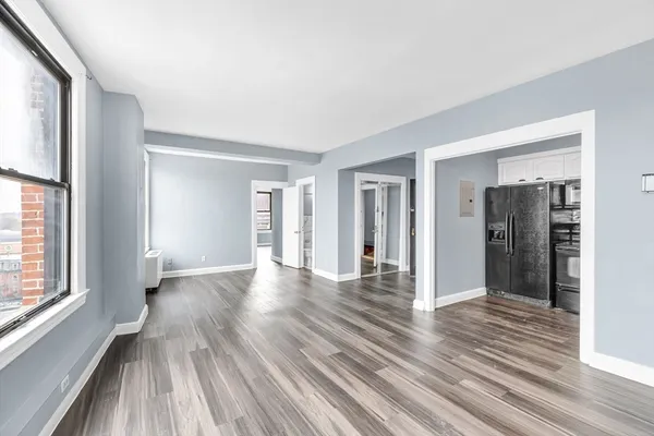a view of an empty room with wooden floor and a window