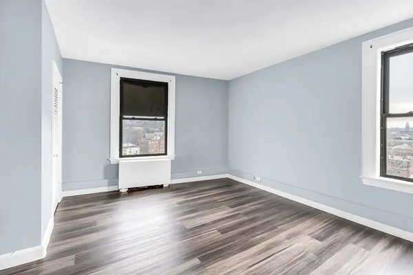 an empty room with wooden floor and windows