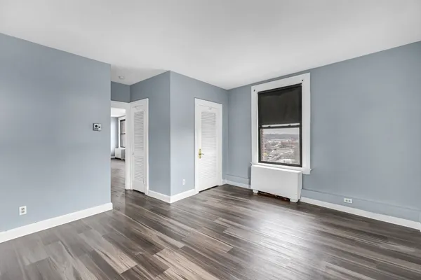 an empty room with wooden floor and windows