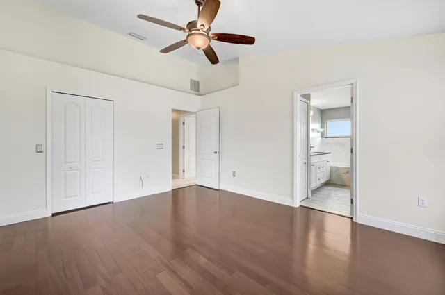 an empty room with wooden floor ceiling fan and windows