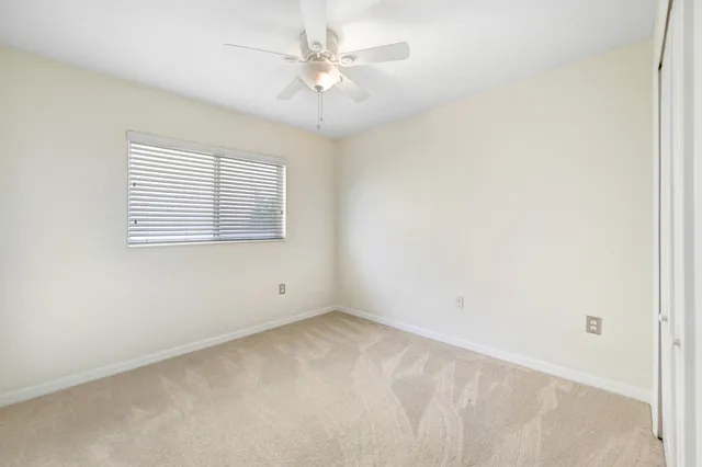 an empty room with a chandelier fan and windows