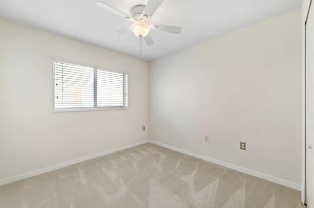 an empty room with a window and a fan
