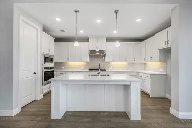 a large kitchen with granite countertop a large counter top a sink stainless steel appliances and cabinets