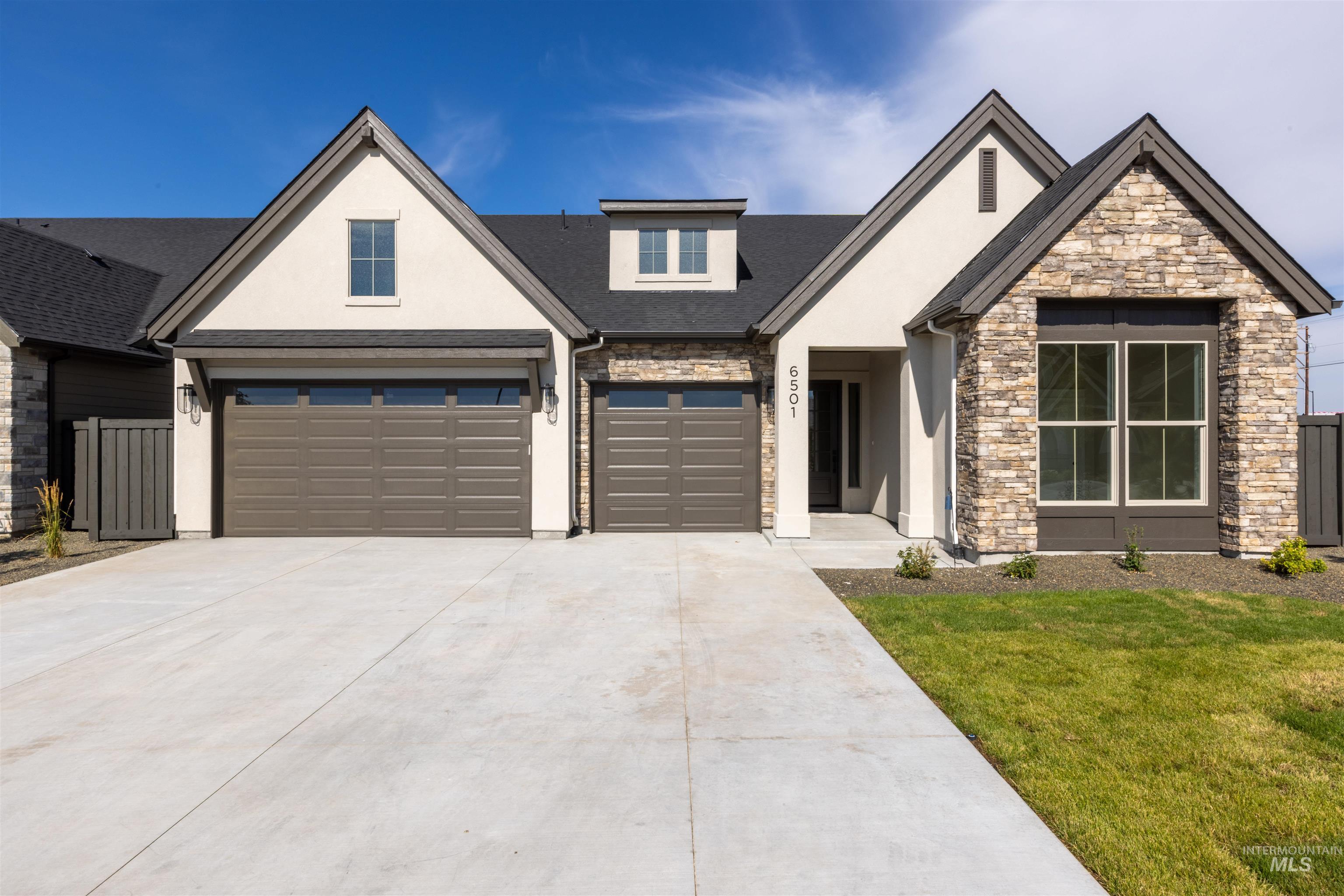 View of front facade with stucco siding, stone siding, driveway, and a garage