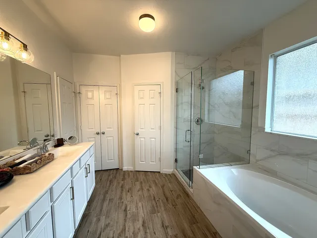 a bathroom with a tub sink shower and two mirror