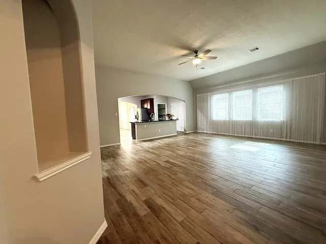 an empty room with wooden floor and windows