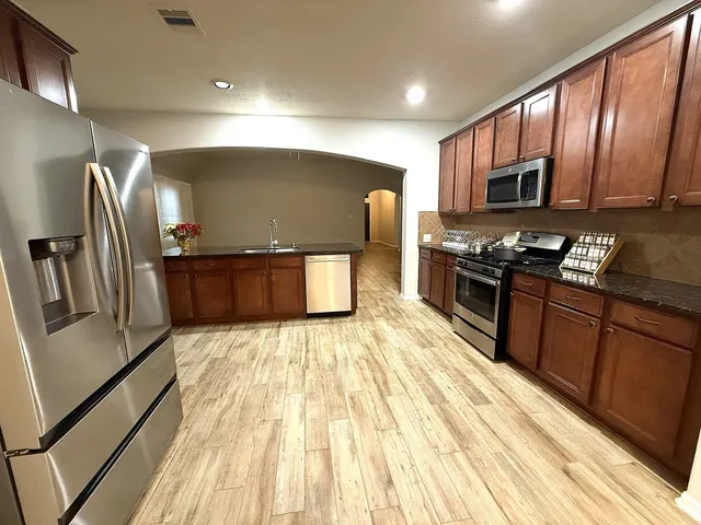 a kitchen with stainless steel appliances granite countertop a refrigerator a stove top oven a sink and dishwasher