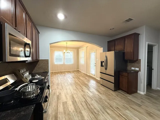 a kitchen with stainless steel appliances granite countertop a stove a refrigerator a sink and dishwasher with wooden floor