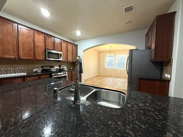 a kitchen with stainless steel appliances granite countertop a sink a stove a microwave a refrigerator and cabinets