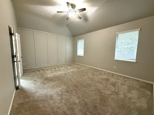an empty room with windows and fan