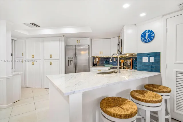 a kitchen with stainless steel appliances kitchen island a refrigerator sink and cabinets