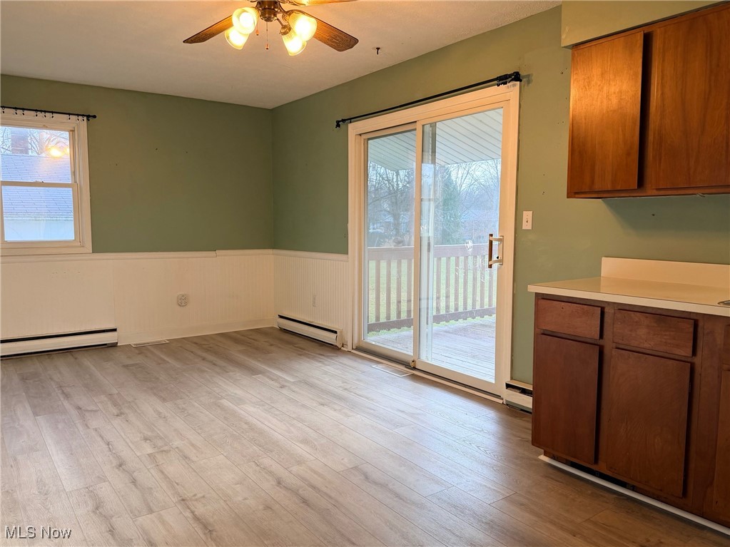 4556 Fishcreek Road Stow, OH 44224 - Photo 29 of 41 Unfurnished dining area featuring wainscoting, light wood-style floors, a baseboard heating unit, and ceiling fan