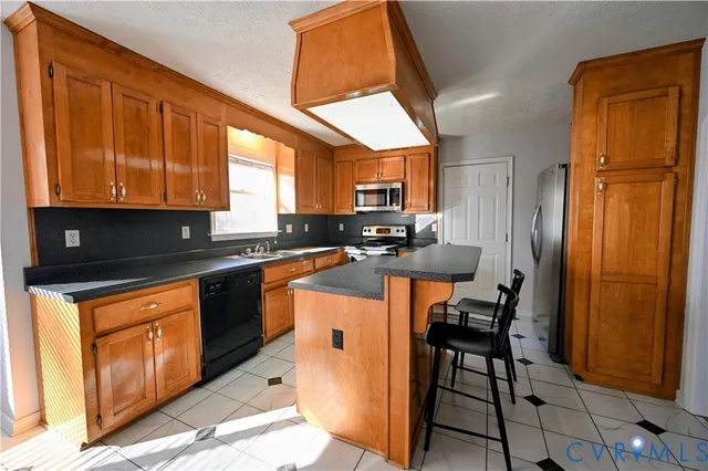 a kitchen with stainless steel appliances granite countertop wooden cabinets a refrigerator a sink a stove a dining table and chairs