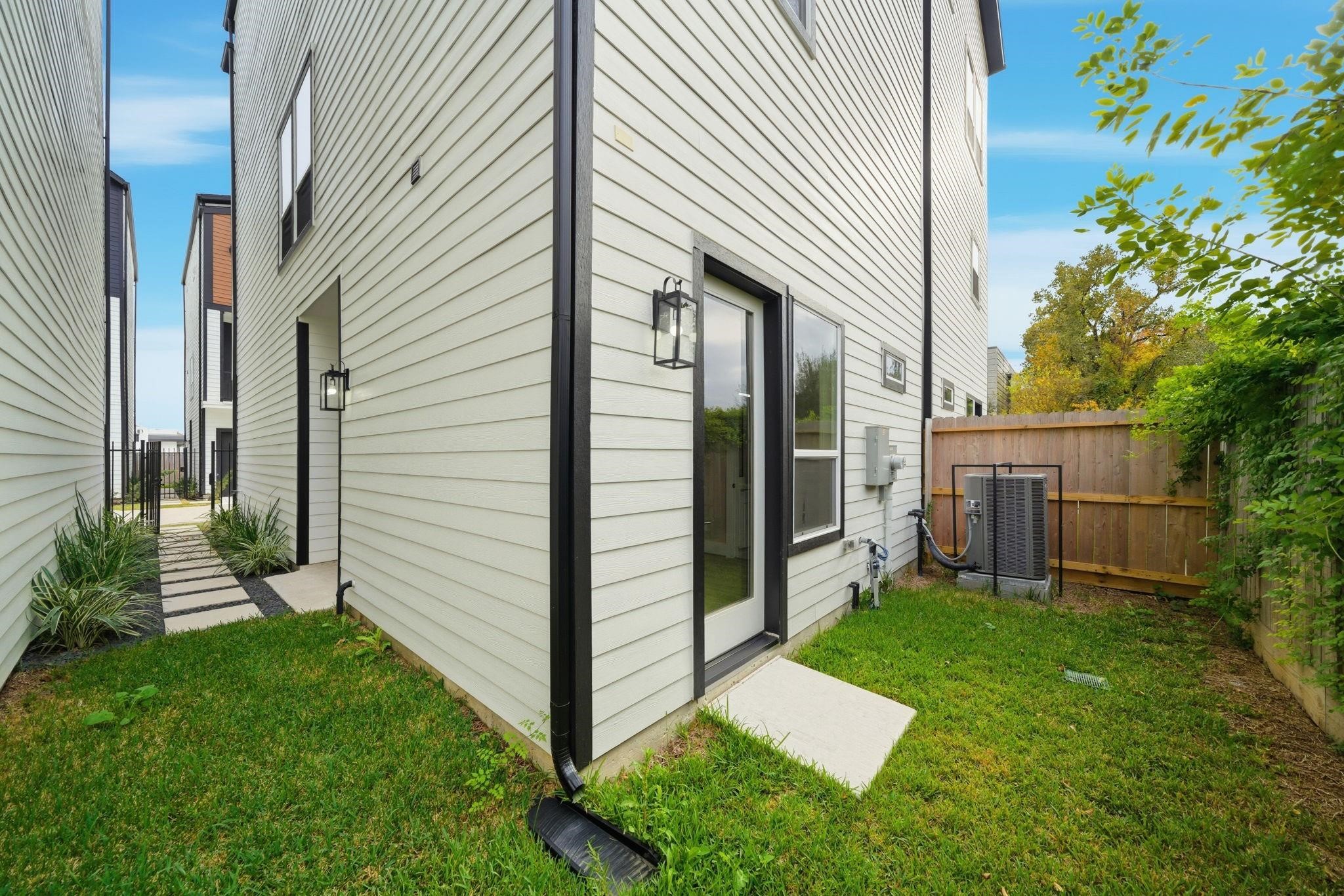 4013 Griggs Road, Unit F Houston, TX 77021 - Photo 4 of 35 Modern side yard with a fenced area, featuring sleek exterior lighting and well-maintained greenery, offering a private outdoor space.