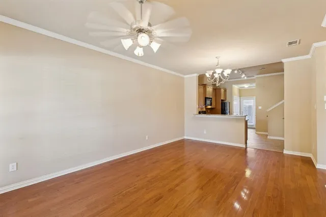 an empty room with wooden floor and chandelier