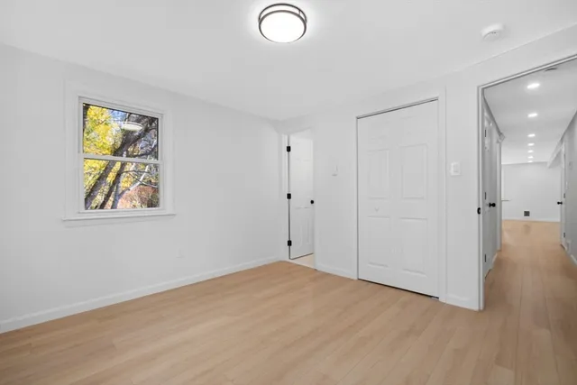 a view of empty room with wooden floor and window