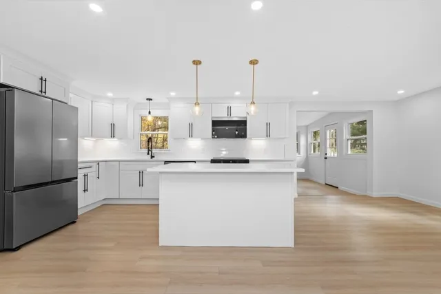 a kitchen with stainless steel appliances granite countertop a refrigerator a sink dishwasher a oven with white cabinets and wooden floor