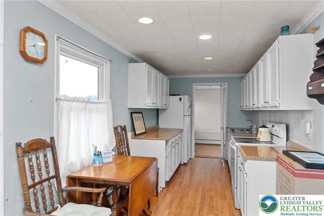 a kitchen with stainless steel appliances granite countertop a stove a sink a refrigerator and a dining table with wooden floor