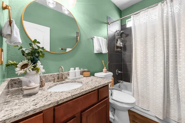 a bathroom with a granite countertop sink a toilet and a mirror