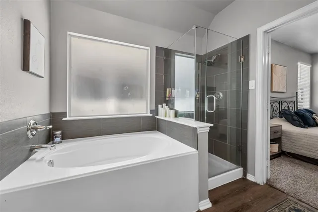 a bathroom with a tub a sink a mirror and a shower