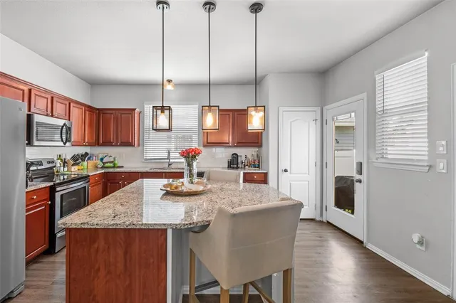a kitchen with stainless steel appliances granite countertop a sink a stove and chairs