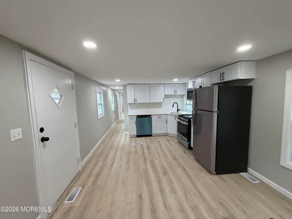a view of a kitchen with a refrigerator a stove top oven and wooden floor
