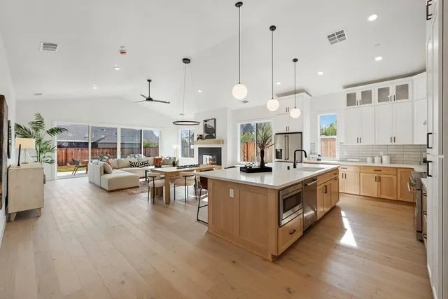 a kitchen with stainless steel appliances wooden floor and a sink