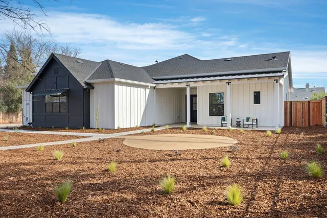a view of a house with a yard and large tree
