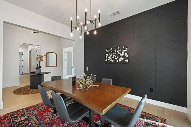 a kitchen with stainless steel appliances granite countertop a sink a stove a refrigerator a dining table and chairs with wooden floor