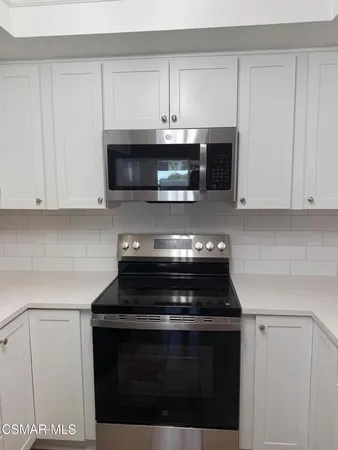 a kitchen with microwave a stove and cabinets