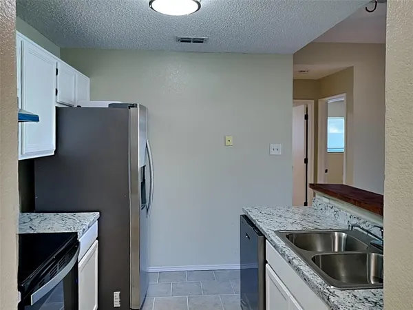 a kitchen with granite countertop a refrigerator and a sink
