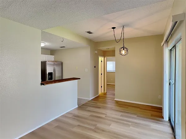 a view of a hallway with wooden floor and a kitchen