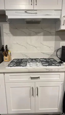 a close view of stove kitchen with granite countertop white cabinets and a stove