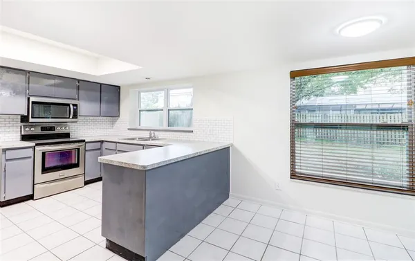 a kitchen with kitchen island granite countertop a sink and a stove top oven