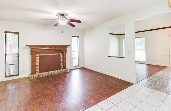 an empty room with wooden floor fireplace and windows