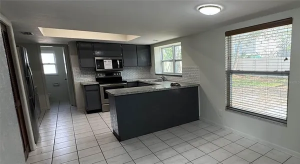 a kitchen with granite countertop a stove a sink and a refrigerator