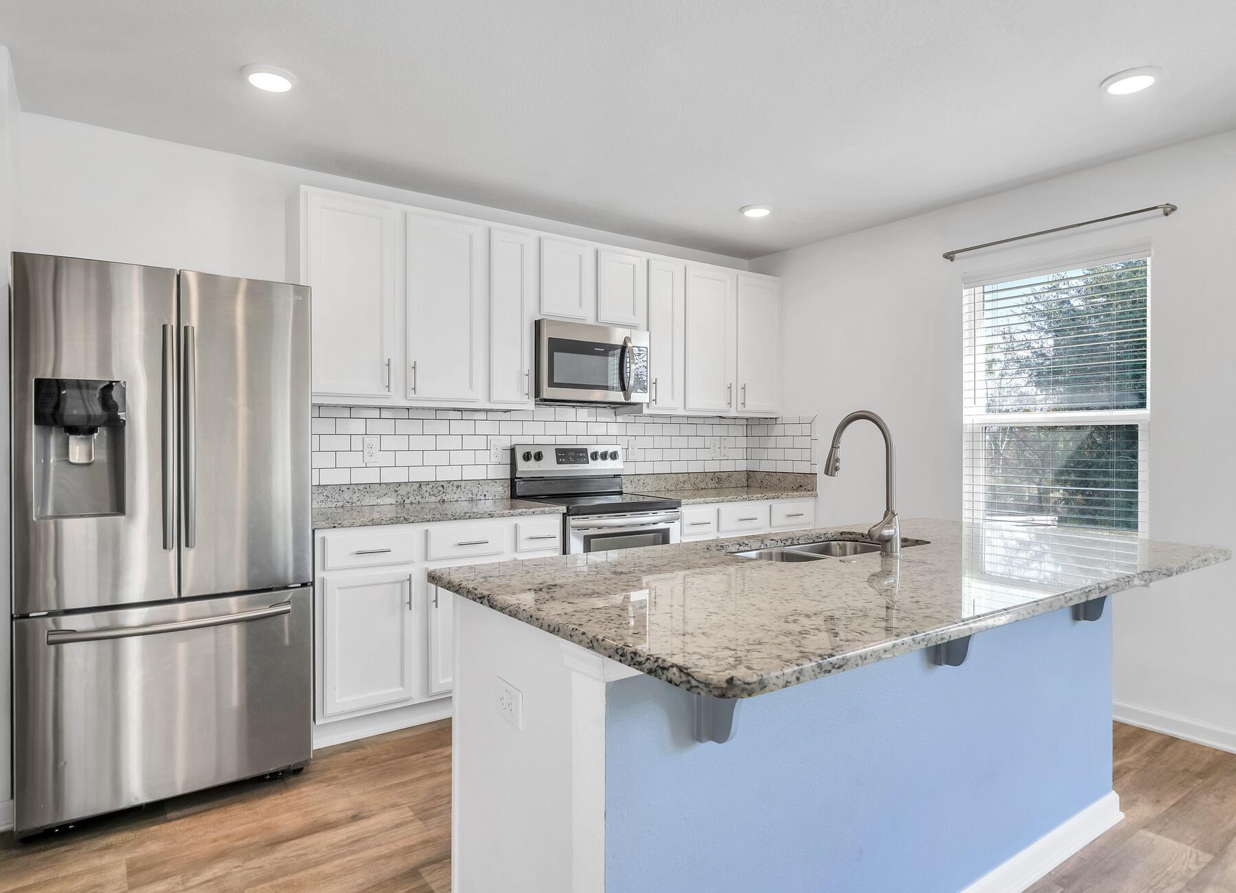 955 Merganser Way Crestview, FL 32539 - Photo 5 of 34 a kitchen with kitchen island granite countertop a stove a sink a refrigerator a center island and wooden floor
