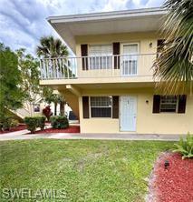Back of property with stucco siding, a balcony, and a lawn