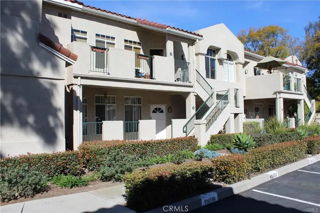 a view of white house with a small yard and potted plants