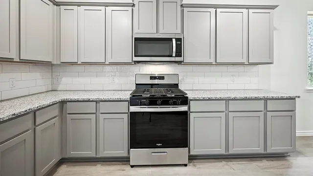 a kitchen with granite countertop white cabinets stainless steel appliances and a sink
