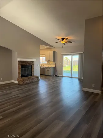 an empty room with wooden floor a ceiling fan and windows